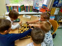 Dzeici siedzą przy stolikach i grają w szachy