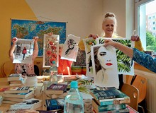 Na zdjęciu Ewa prezentuje przepiękne obrazy wyszywane haftem krzyżykowym