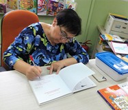 Pisarka składa autograf w książce należącej do biblioteki