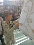 chłopiec przykleja liście do wspólnego jesiennego drzewa
