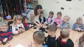 Dzieci wykonują prace plastyczne przy stolikach