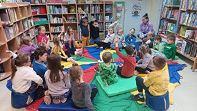 Dzieci podczas wspólnej zabawy siedzą na chuście animacyjnej