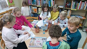 Dzieci w czytelni przeglądają książeczki, grają w gry i układają puzzle