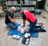 Pani Izabela Wesołowska ćwiczy udzielanie pierwszej pomocy pod okiem ratownika medycznego