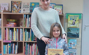 Dziewczynka z bibliotekarką prezentują książeczkę