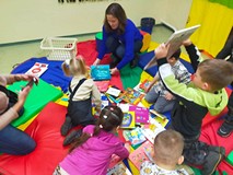 Dzieci wyszukują wybranej książki z pozostałych, rozłożonych na chuście animacyjnej