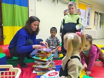 Dzieci z bibliotekarką układają wieżę z książek