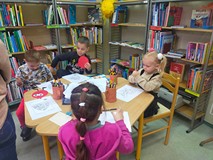 Dzieci koloruja kolorowanki w czytelni bibliotecznej