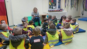 Dzieci słuchają opowiadania czytanego przez bibliotekarkę