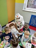 Olaf z najmniejszym żłobkowiczem ogląda i pokazuje książeczkę kontrastową