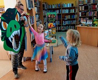 Przedszkolaki karmią T-rexa wrzucając woreczek w paszczę dinozaura