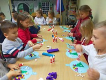 Dzieci wykonują prace plastyczne przy stolikach