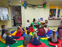 Dzieci siedzą w kole na kolorowej chuście i słuchają opowiadania