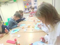 Dzieci wykonują prace plastyczne przy stolikach