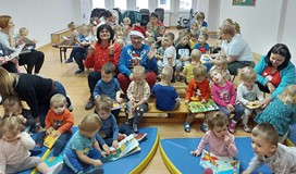 Wiola i Gosia pozują do zdjęcia, siedząc wśród żłobkowych maluchów