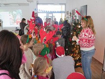 Prowadząca zajęcia bibliotekarka opowiada dzieciom o zwyczajach bożonarodzeniowych.