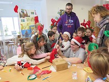 Bibliotekarz pomaga dzieciom zrobić przypinki z ich ilustracjami.