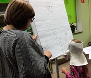 Dziewczynka z zasłoniętymi oczami próbuje narysować misia