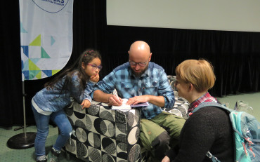 Adam Jarniweski z córką Kają składa autograf w książce swojego autorstwa