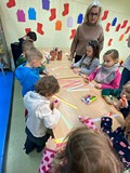 Dzieci stoją przy stolikach i wykonują prace plastyczne