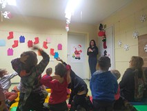 Dzieci siedzą na materacach i omawiaja stroj Św. Mikołaja