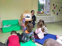 Dzieci siedzą na materacach podczas teatrzyka Kamishibaj