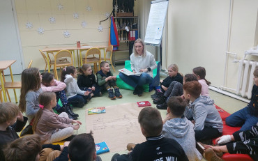 Dzieci słuchają opowiadania, które czyta im bibliotekarka