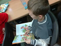 Chłopiec czyta na głos fragment książki o Kybusiu Puchatku
