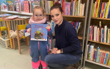 Dziewczynka i bibliotekarka prezentują książeczkę