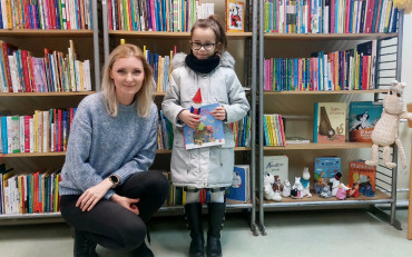 Dziewczynka pozuje z bibliotekarką trzymając książkę