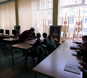 na zdjęciu dzieci słuchają co mówi bibliotekarka