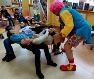 Na zdjęciu dzieci wykonują karkołomne sztuczki pod nadzorem klauna