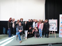 Na scenie siedzi Marcin Mortka z licealistami przybyłymi na spotkanie autorskie