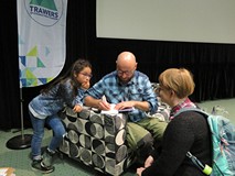 Na scenie siedzi Adam Jarniewski z córką i podpisuje książkę czytelniczce