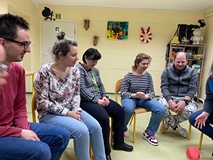 Uczesticy siedzą na krześle i rzucają kostką