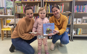 Bibliotekarki i dziewczynka prezentują książeczkę