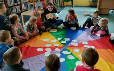 bibliotekarka czyta opowiadanie, dzieciom siedzącym na chuście
