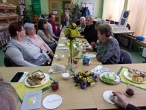 na zdjęciu zebrali siedzą przy stołach i rozmawiają