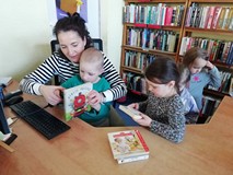 chłopiec wypożycza książkę w asyście bibliotekarki