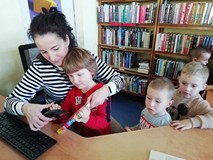 chłopiec wypożycza książkę w asyście bibliotekarki