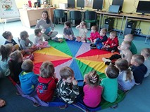 bibliotekarka czyta książkę dzieciom siedzącym na chuście