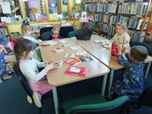 dzieci siedzą przy stole i oglądają książki