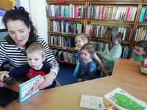 chłopiec wypożycza książkę w asyście bibliotekarki