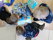 Dzieci oglądają książki siedząc na podłodze