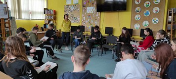 dzieci rysują na kartkach siedząc na krzesłach