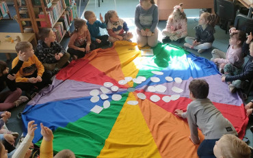 bibliotekarka czya dzieciom siedzącym na chuście książkę