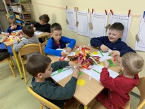 Dzieci siedzą przy stolikach i wykonuja prace plastyczną