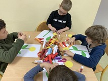 Dzieci siedzą przy stolikach i wykonuja prace plastyczną