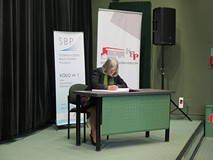 Zasłużona bibliotekarka składa podpis w Księdze zasłużonych w czasie Dnia Bibliotekarza w Koszalińsk