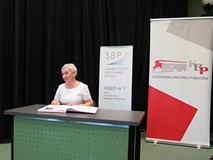 Zasłużona bibliotekarka składa podpis w Księdze zasłużonych w czasie Dnia Bibliotekarza w Koszalińsk